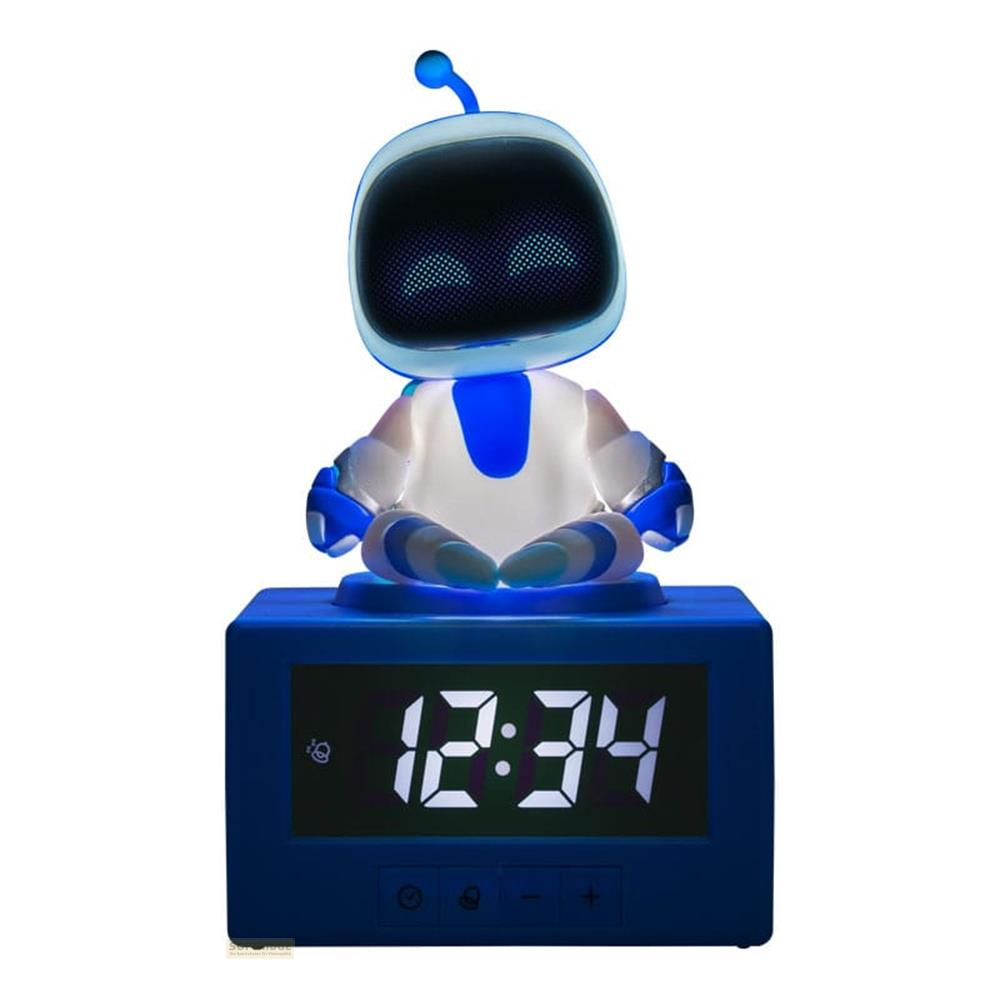 Niebieski cyfrowy budzik z siedzącym na nim małym robotem.