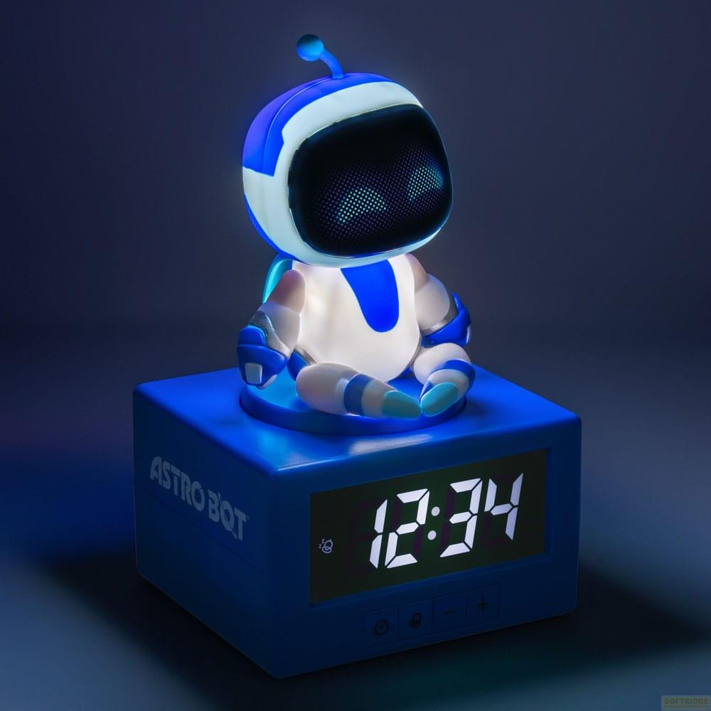 Niebieski robot siedzi na cyfrowym budziku pokazującym 12:34.