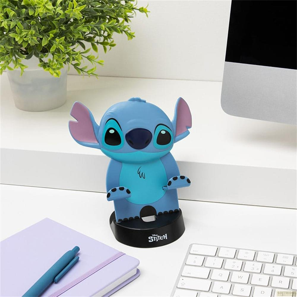 Niebieski stojak Stitch z ciemną podstawą stoi na biurku obok notatnika i klawiatury.