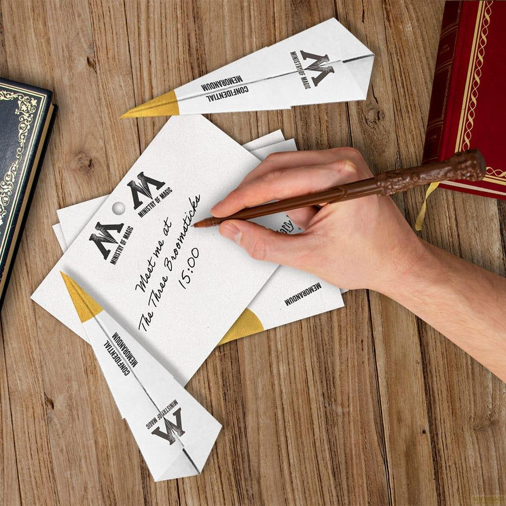 Main écrit une note sur papier avec un stylo baguette. Papeterie Ministry of Magic.