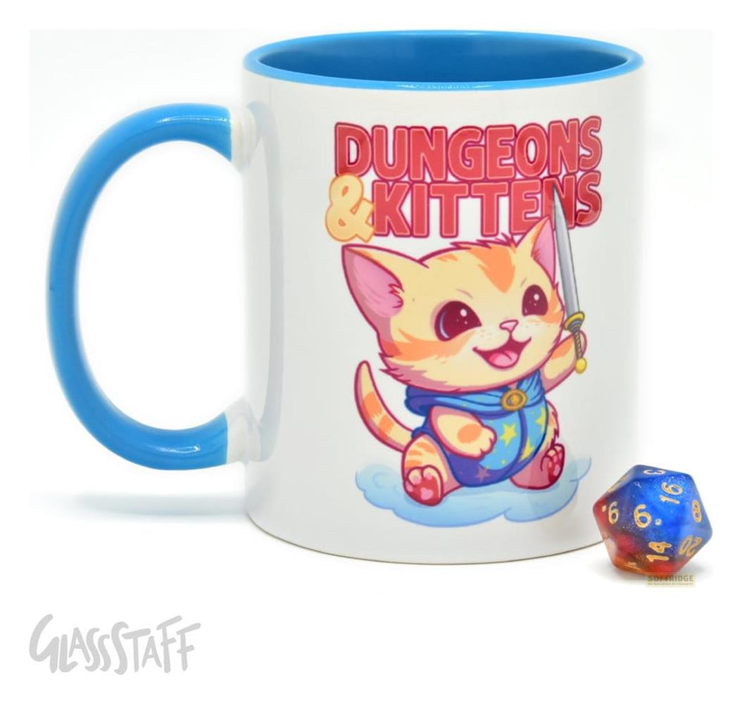 Una taza blanca con asa azul que muestra un gato de dibujos animados, el texto 'Dungeons & Kittens' y un dado azul al lado.