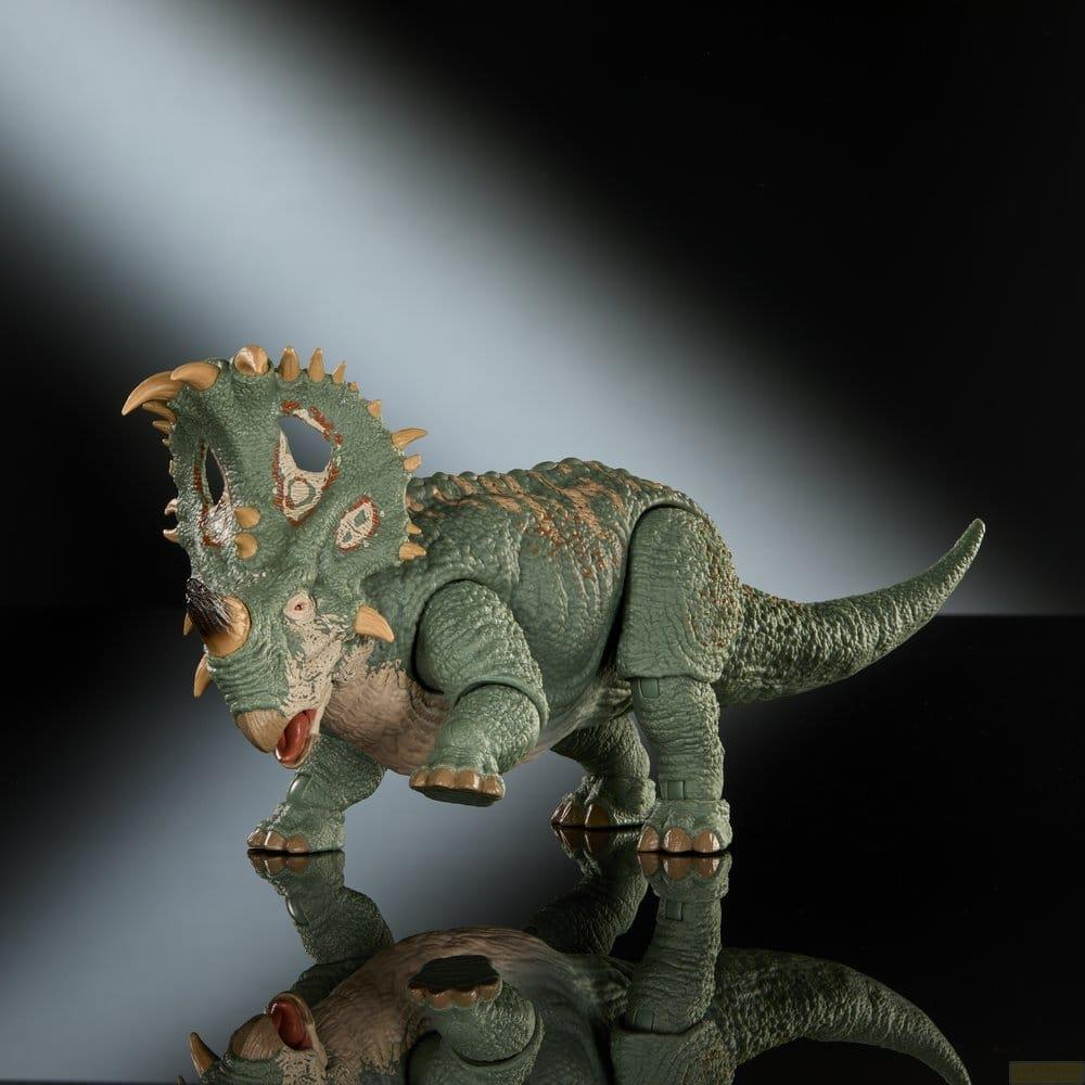 Grüner Dinosaurier Spielzeug mit Hörnern und Nackenschild auf schwarzem Hintergrund.