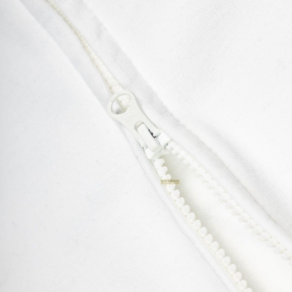 Primer plano de una cremallera blanca sobre tela blanca. Los dientes de la cremallera son visibles.