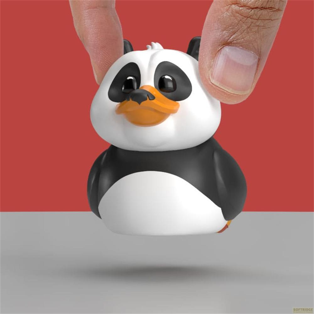 Ein kleiner Panda-Gummi-Enten-Spielzeug wird von Fingern gehalten, rot-grauer Hintergrund.