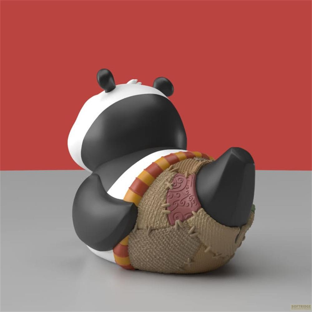 Ein Panda-Spielzeug sitzt auf einem grauen Untergrund vor rotem Hintergrund. Es trägt ein Flickenteil.