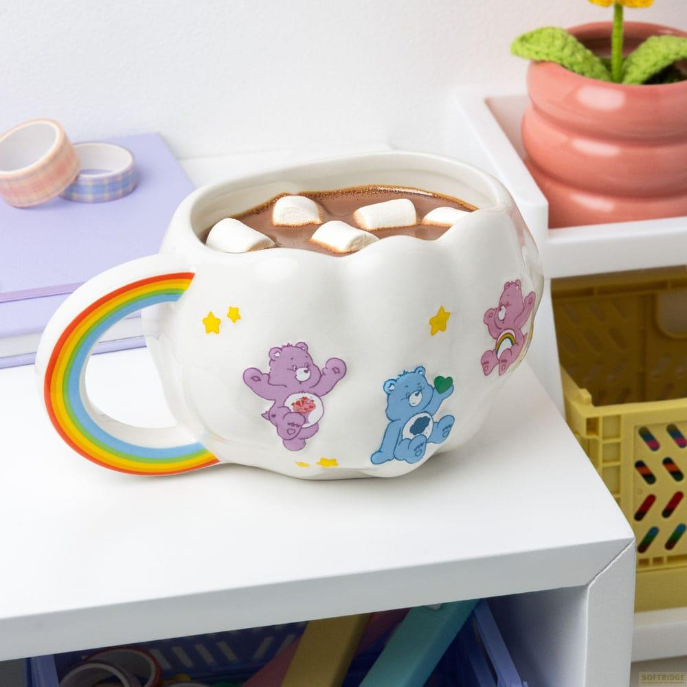 Taza blanca con asa de arcoíris, llena de chocolate caliente y malvaviscos, con Care Bears.