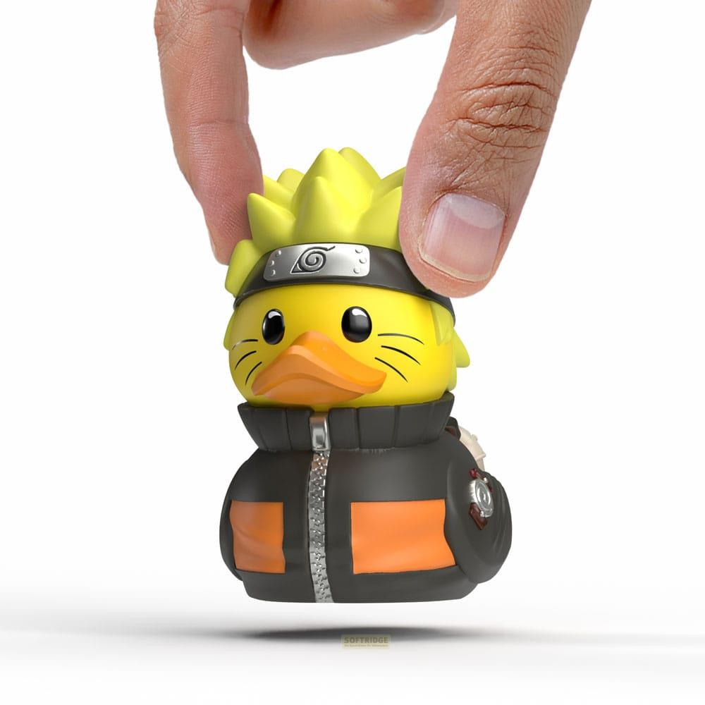 Un patito de goma amarillo con el peinado y la cinta de Naruto es sostenido por dedos.