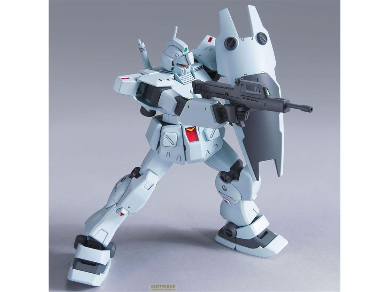 Un robot Gundam bleu clair avec fusil et bouclier en pose de combat.