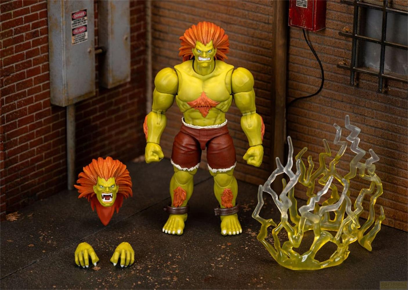 Action figure con pelle gialla, pantaloncini rossi e capelli arancioni.