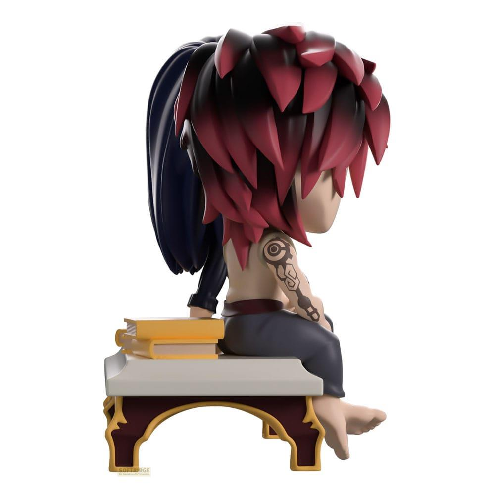 Chibi-Figur mit roten Haaren sitzt auf einem Hocker neben Büchern.