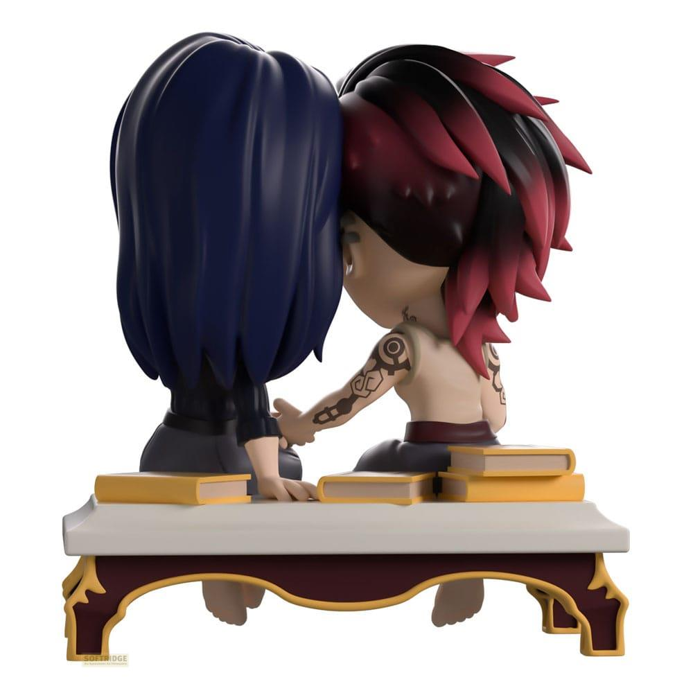 Zwei Anime-Figuren sitzen auf Büchern, eine mit blauen Haaren, die andere mit roten Streifen.