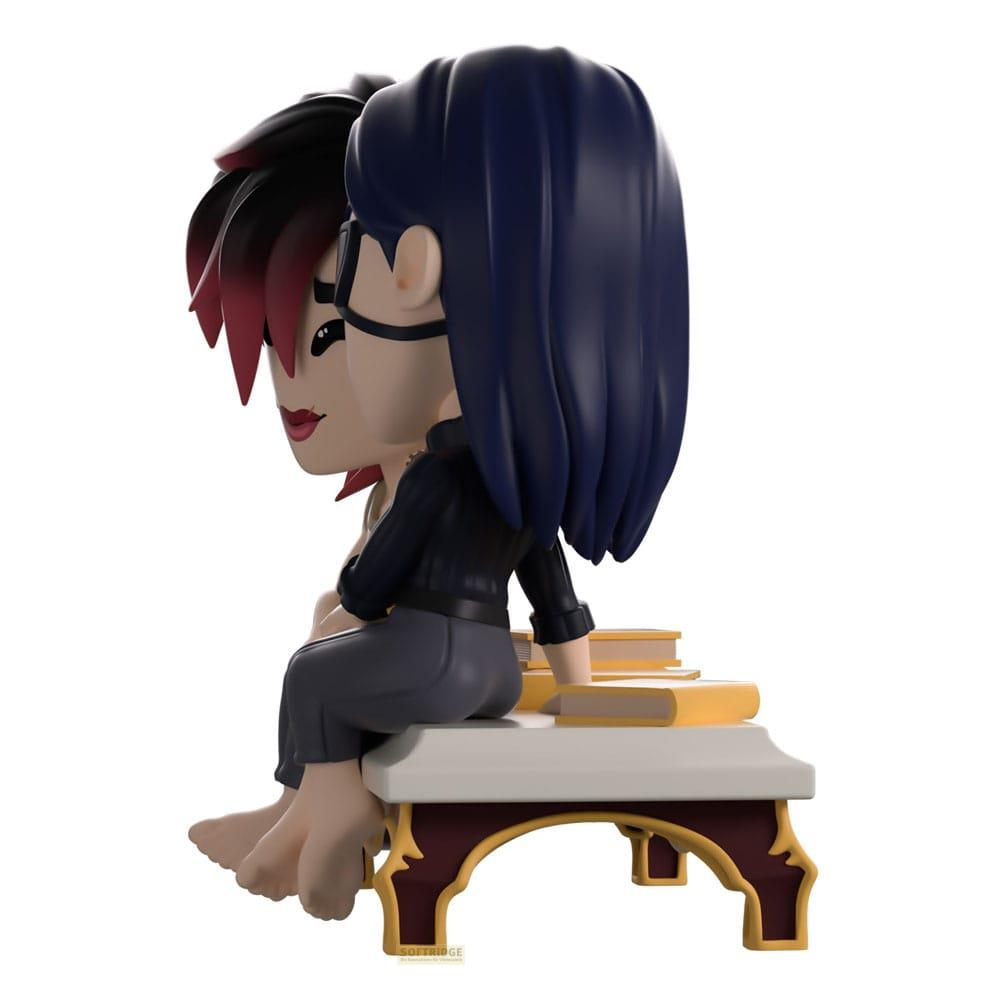 Zwei Figuren sitzen auf Büchern. Eine Figur hat dunkelblaue Haare und eine Brille.