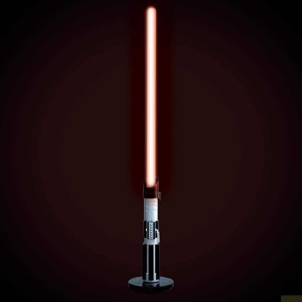 Un sable de luz rojo se alza verticalmente, con un mango plateado y negro.