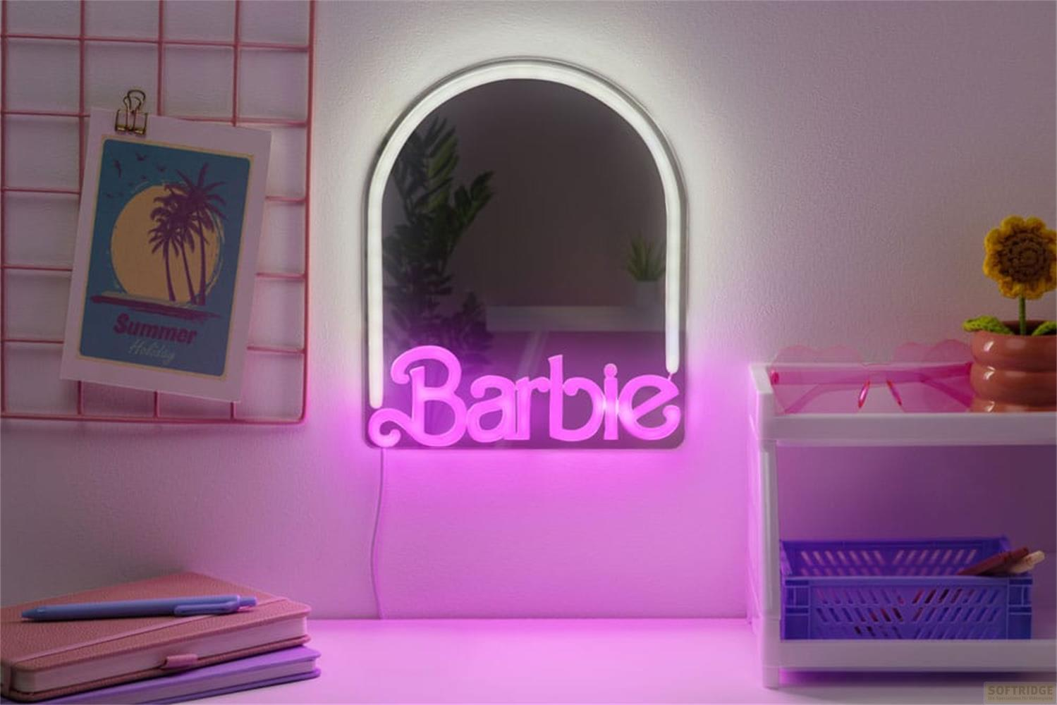 Ein rosa Barbie-Neonlicht leuchtet vor einem Spiegel. Links ein Bild, rechts ein Regal.