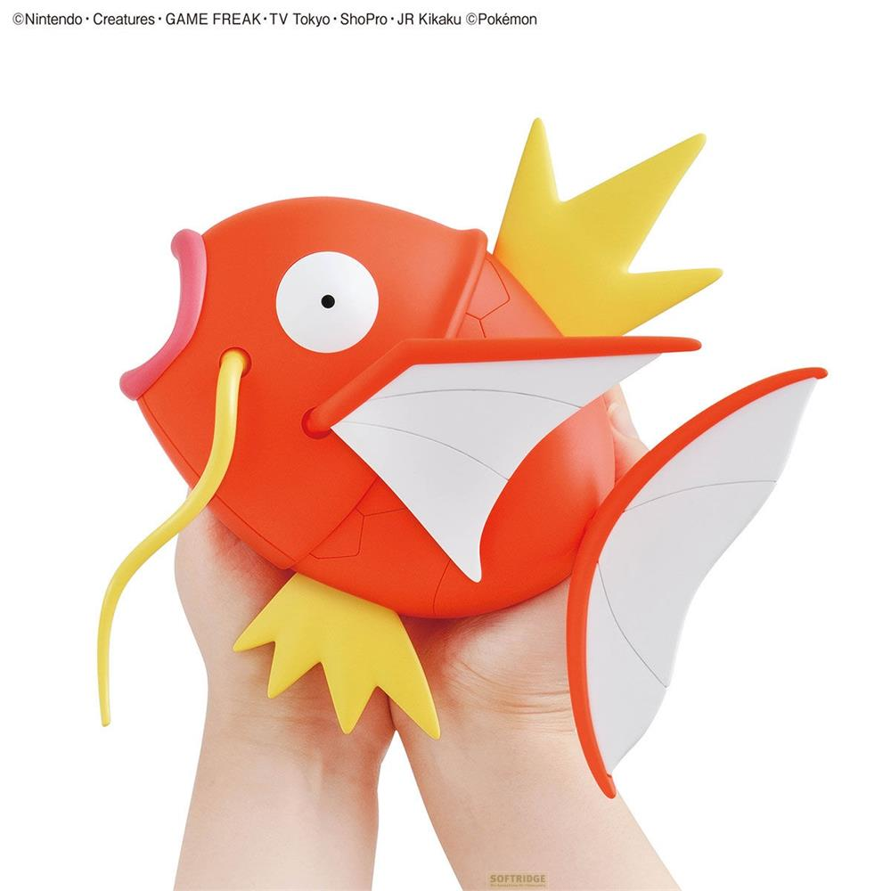 Une figurine Magicarpe orange aux nageoires jaunes est tenue dans des mains.