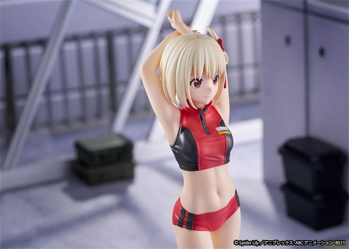 Eine Figur mit blonden Haaren trägt einen roten Sport-BH und Shorts. Sie steht vor einem unscharfen Hintergrund.