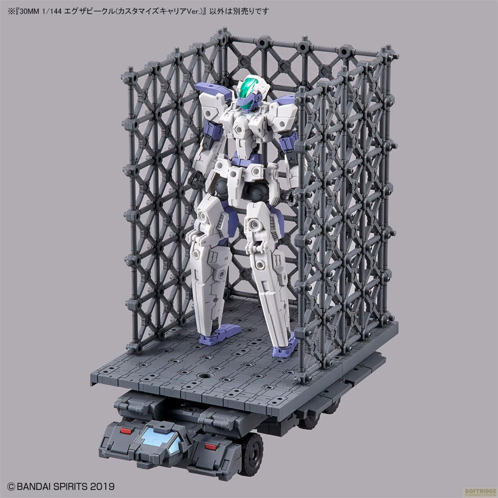Un robot blanc et violet se tient sur une plateforme grise dans une structure de cage.