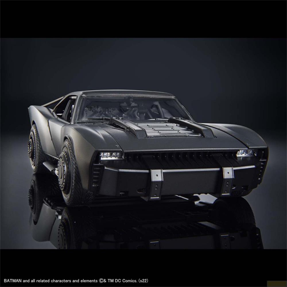 Un modèle noir de Batmobile est exposé sur une surface réfléchissante.