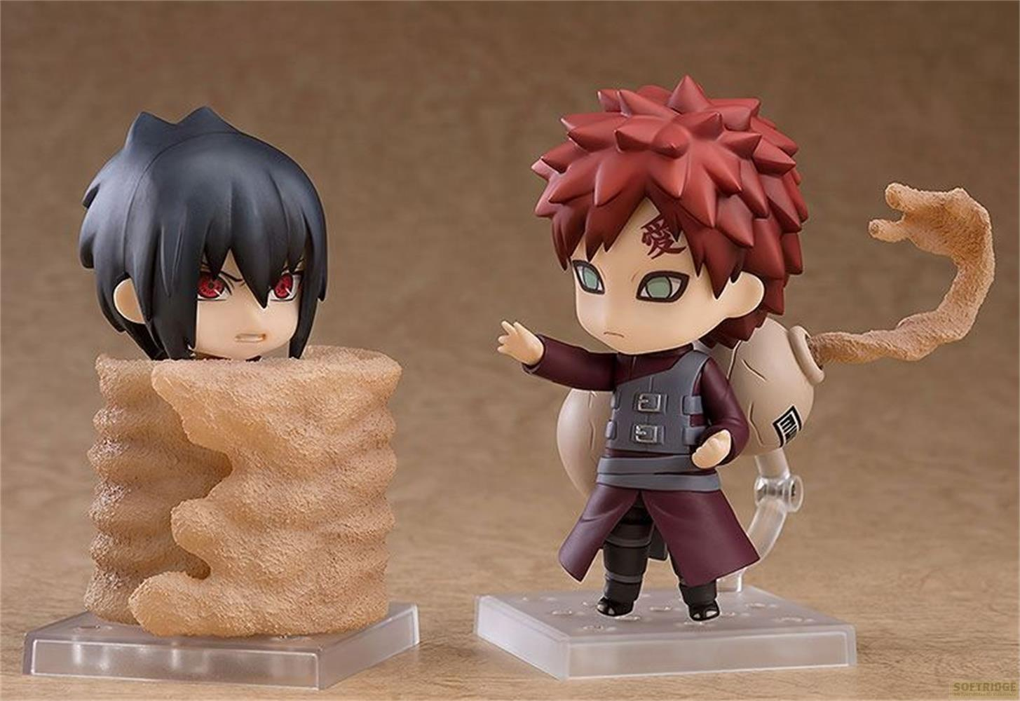 Due action figure anime: Gaara con capelli rossi e braccio di sabbia, Sasuke intrappolato nella sabbia.