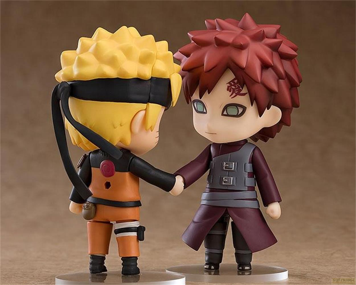 Due action figure anime, Naruto e Gaara, si tengono per mano su sfondo marrone.