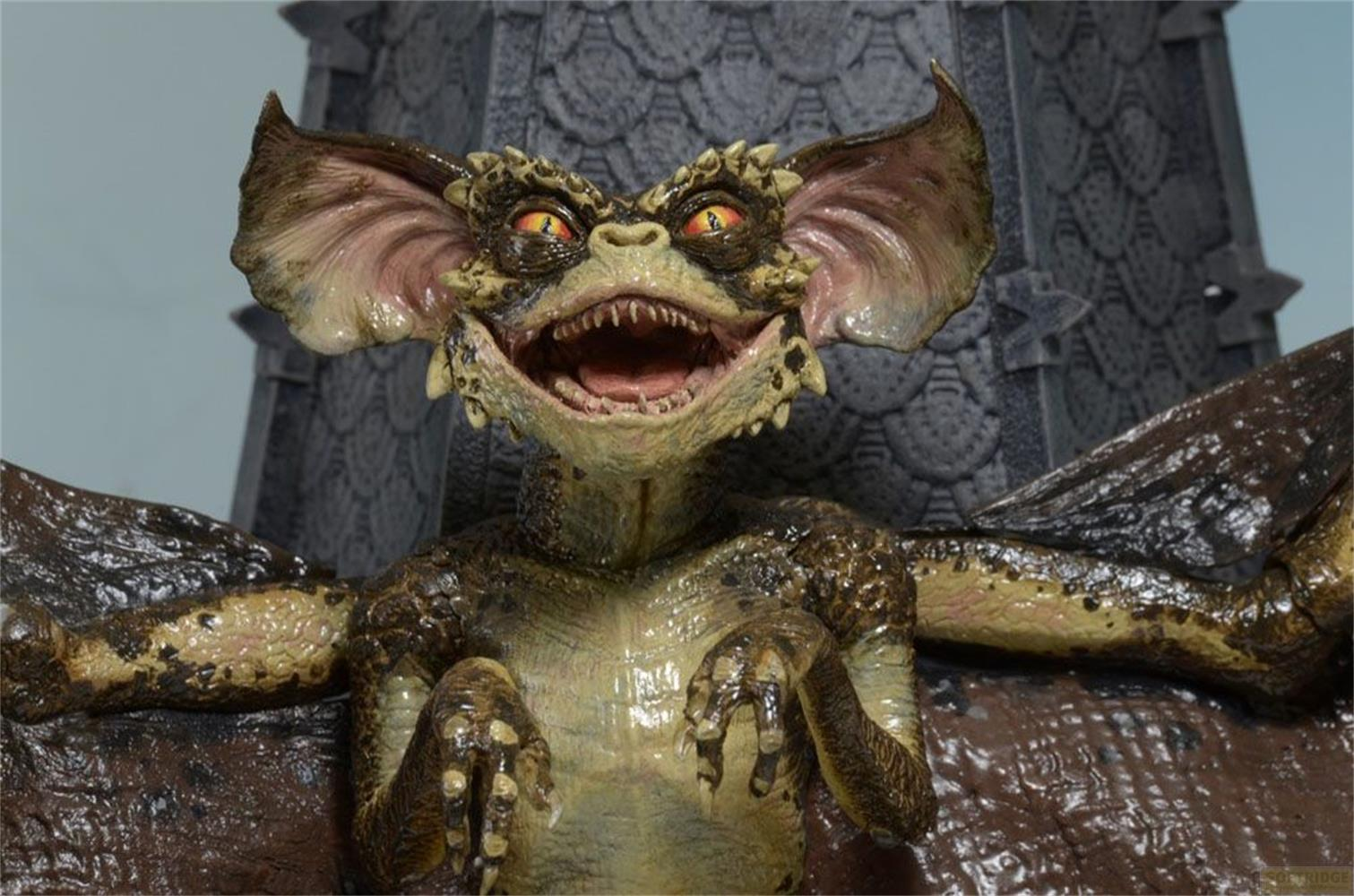 Un gremlin con orejas puntiagudas y ojos amarillos se sienta.