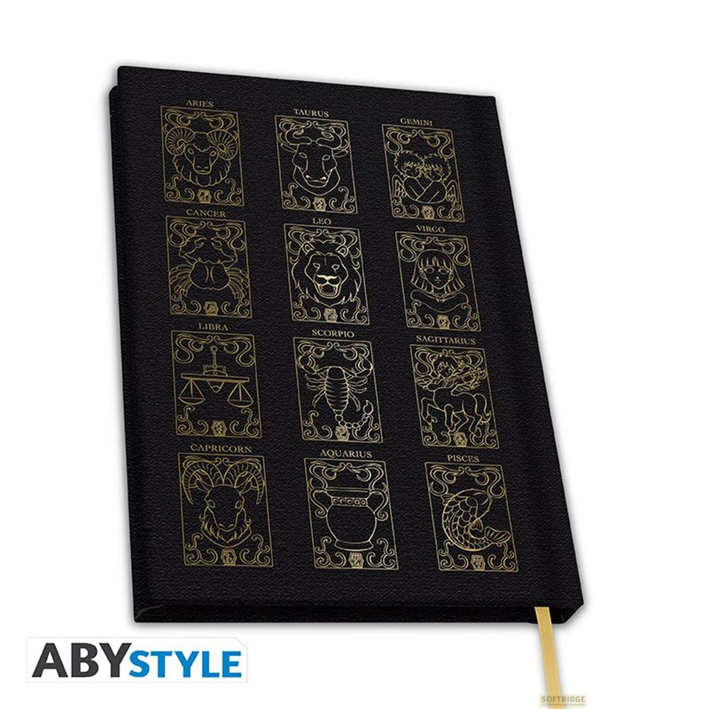Carnet noir avec symboles dorés du zodiaque et noms sur la couverture.