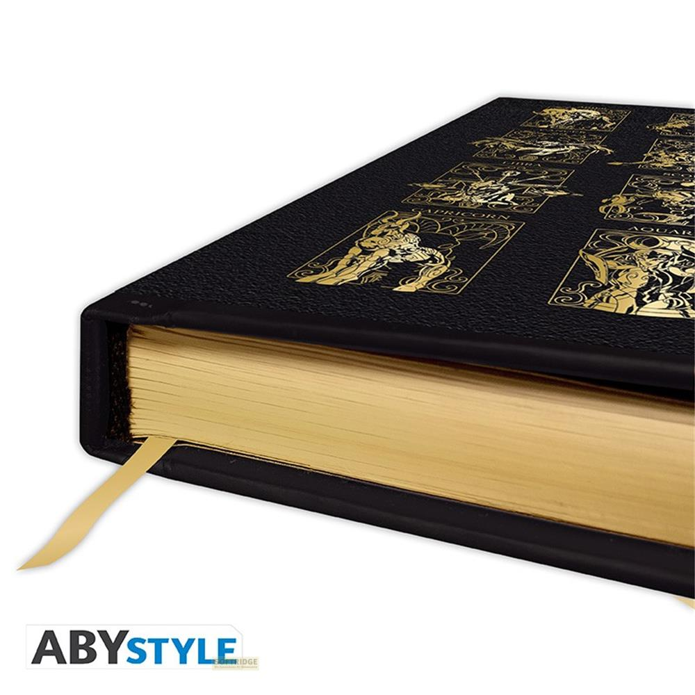Livre noir avec signes du zodiaque dorés sur la couverture et pages dorées.
