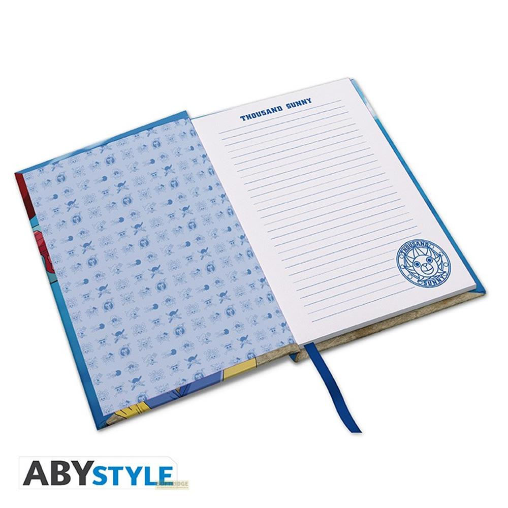 Un carnet ouvert avec une couverture bleue ornée d'un motif de crâne et de pirates.