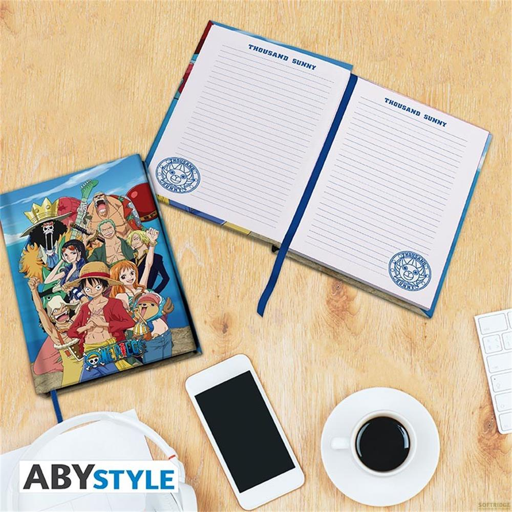 Un carnet ouvert avec art d'anime, smartphone, casque et tasse de café sur un bureau.