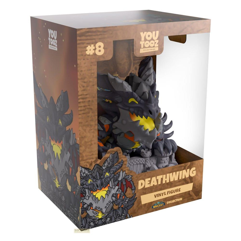 Eine schwarze Drachenfigur mit gelben Akzenten in einer Pappschachtel mit Aufdruck.