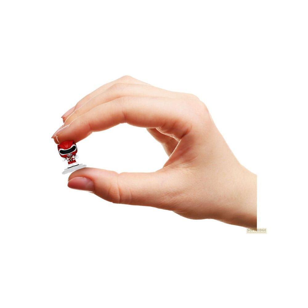 Una mano sostiene una pequeña figura roja de Power Ranger sobre una base blanca.