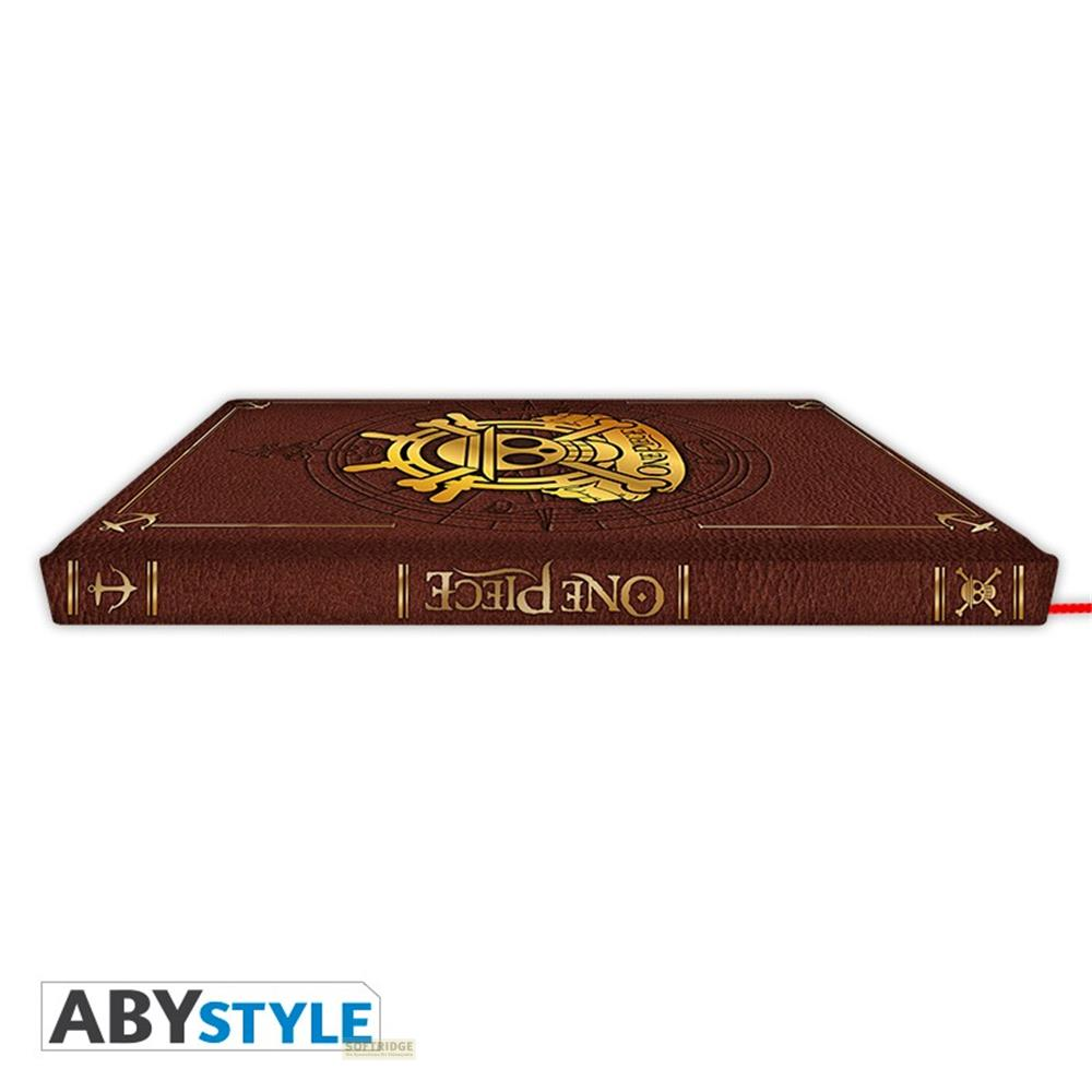 Un livre marron avec un logo doré One Piece et un motif de crâne.