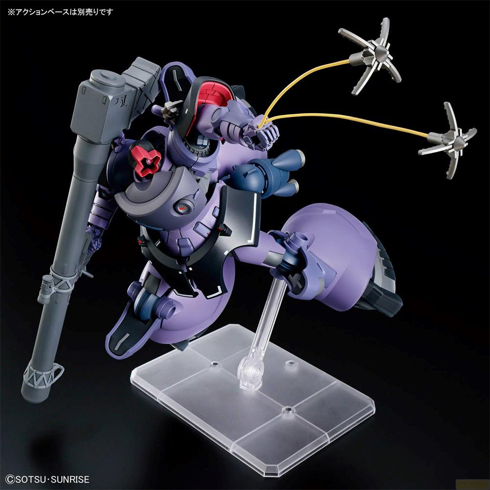 Figurine robot violette avec un pistolet, debout sur un support, sur fond noir.