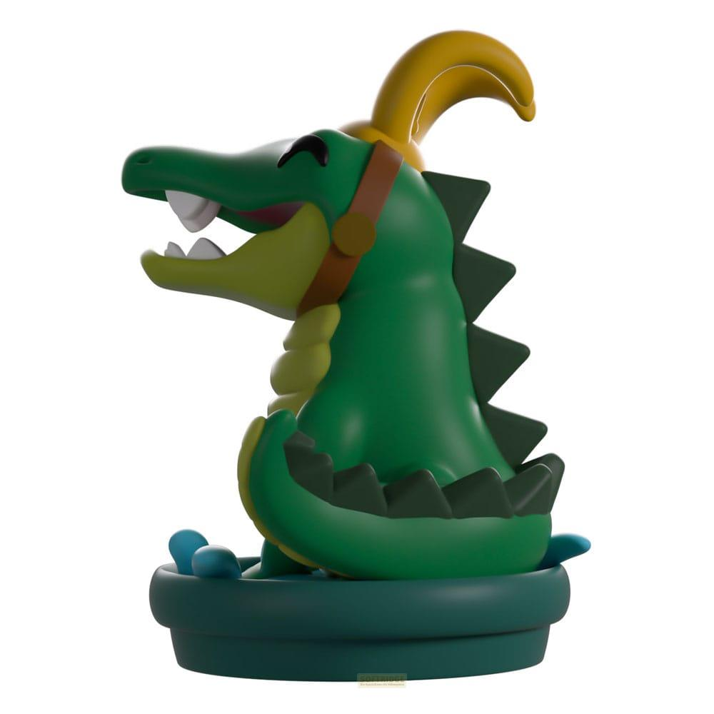 Grüner Krokodil-Figur mit gelbem Horn und braunem Band auf einem grünen Sockel.