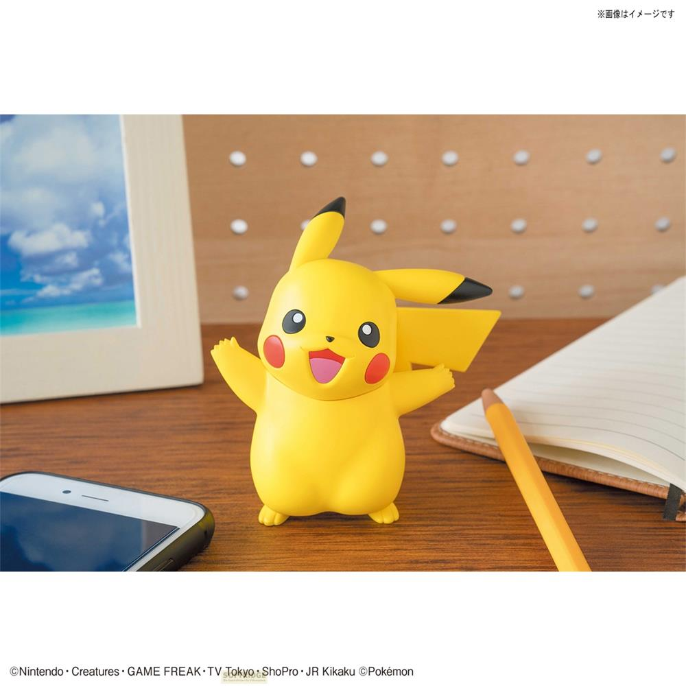 Une figurine jaune de Pikachu se tient sur un bureau en bois, à côté d'un smartphone et d'un carnet.