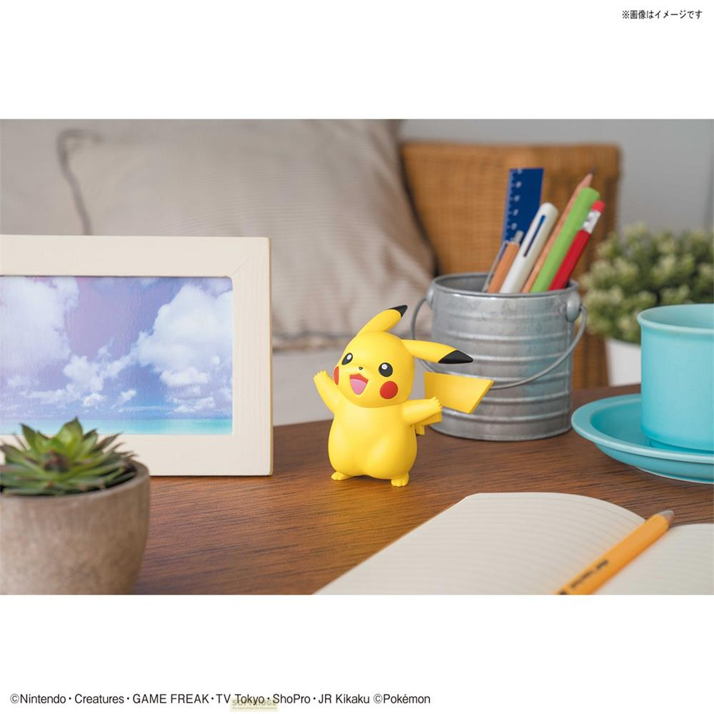 Figurine Pikachu sur table en bois avec cadre photo, pot de plante et stylos.