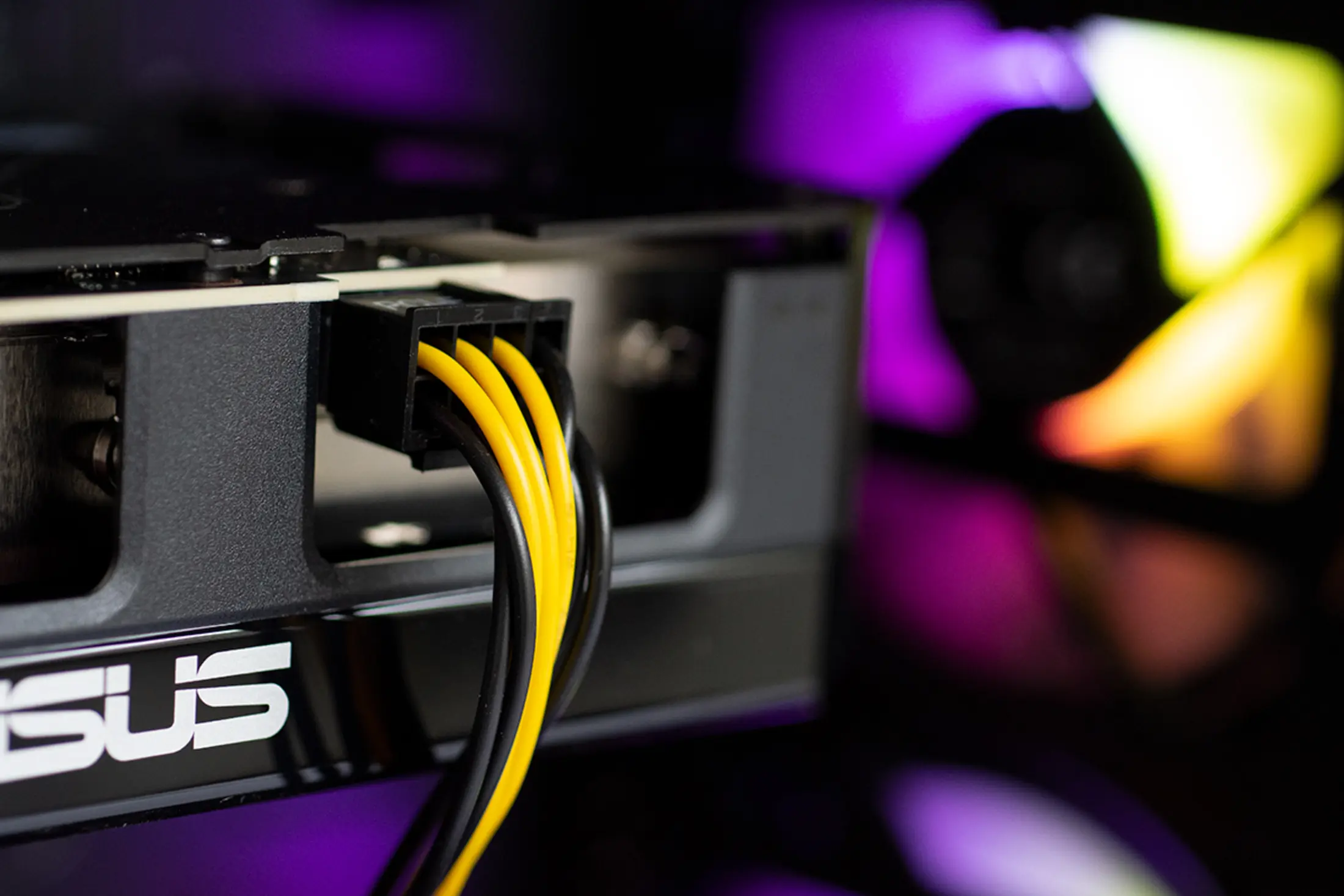 Gele en zwarte draden verbonden met een zwarte poort, ASUS-logo op de voorgrond, paars licht.