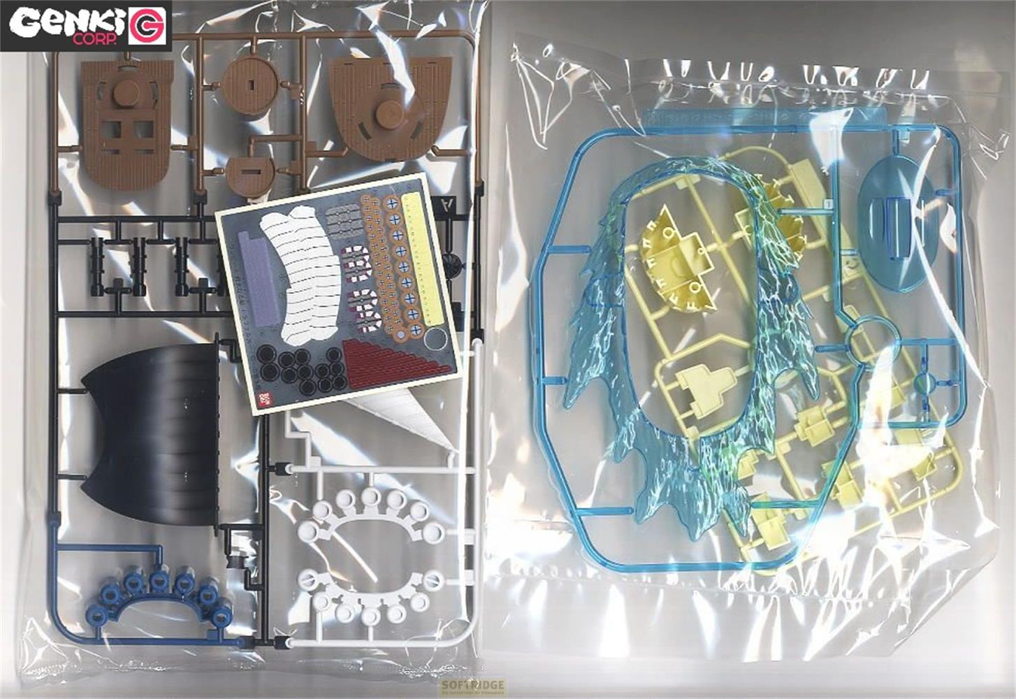 Modellbausatz-Teile in braun, schwarz, blau, weiß und transparent gelb/blau.