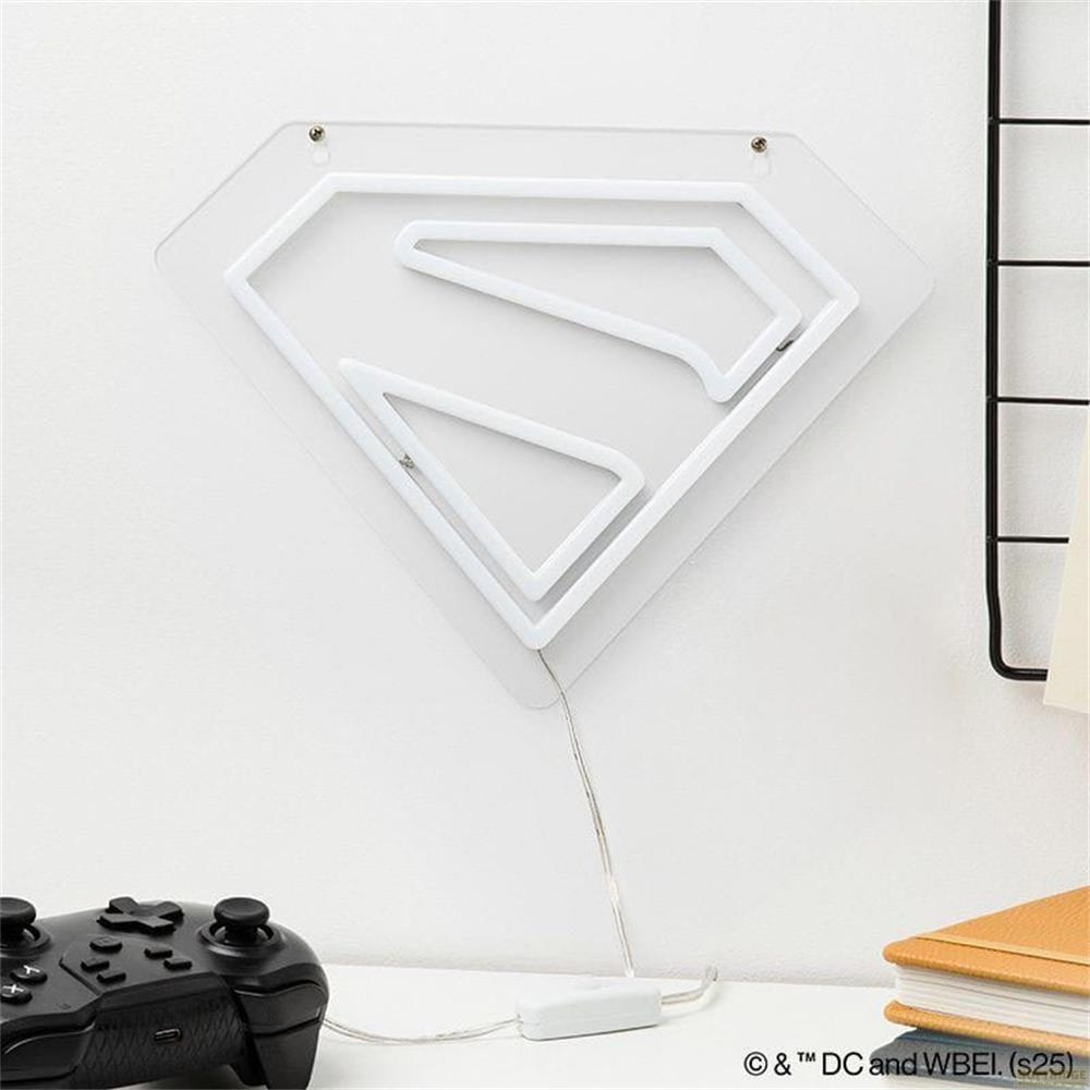 Białe neonowe logo Supermana na białej ścianie, obok kontroler do gier.
