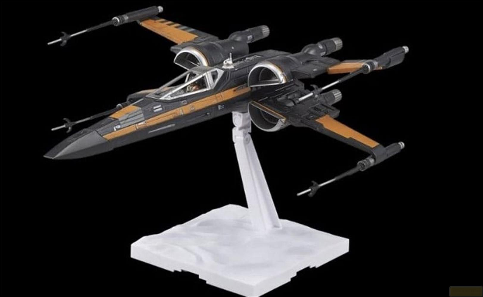 Modèle X-wing noir avec accents orange, sur un socle blanc.