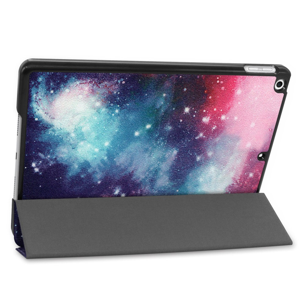 Ein Tablet mit einem galaktischen Hintergrund in einem grauen Ständer.