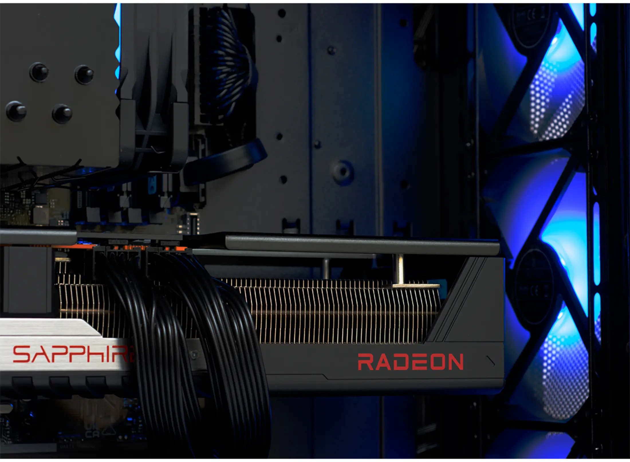 Close-up van een computerinterieur, toont een zwarte grafische kaart met rode "RADEON"-tekst en blauwe LED-ventilatoren.
