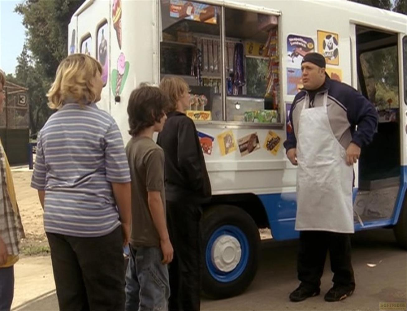 Un venditore di gelati con grembiule sta vicino a un furgone gelati con bambini davanti.
