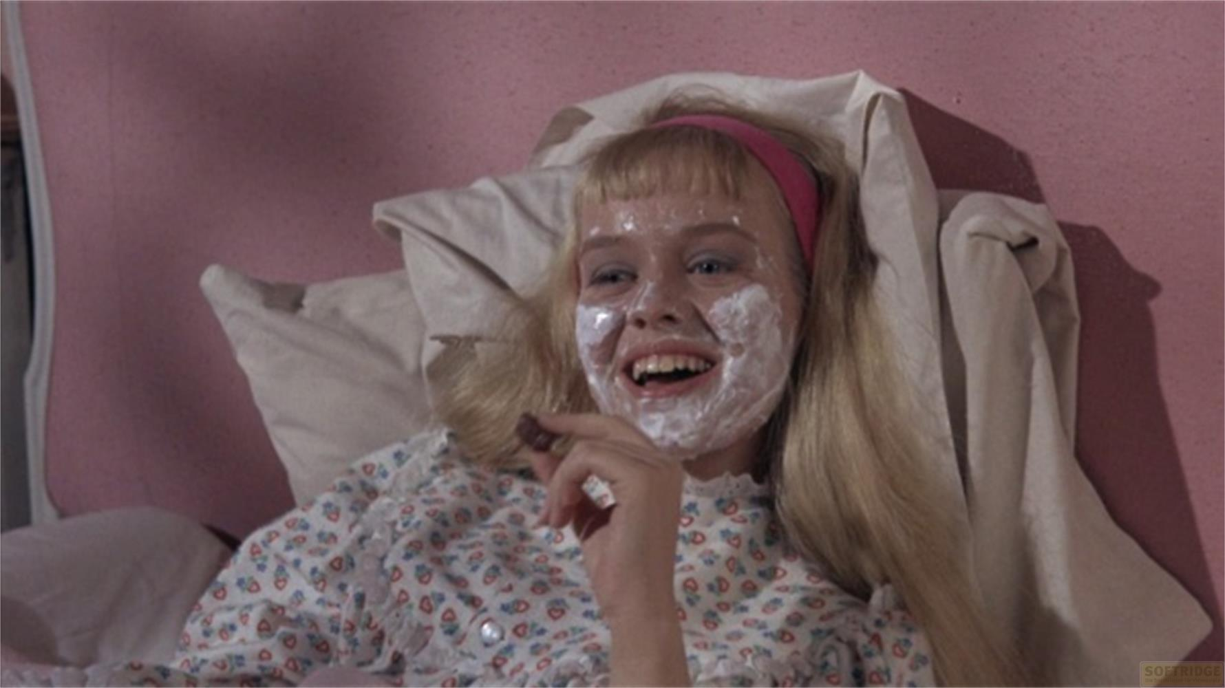 Una ragazza con maschera e fascia giace a letto sorridendo.