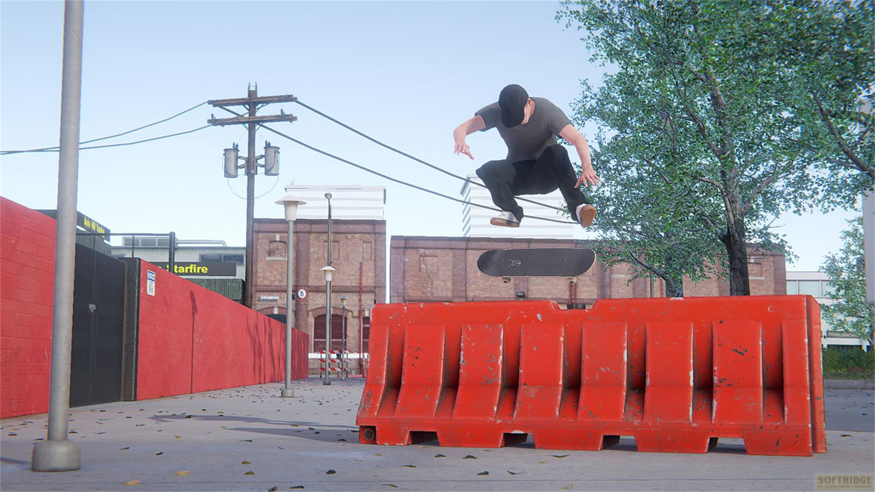 Un skateur saute par-dessus une barrière rouge en milieu urbain.