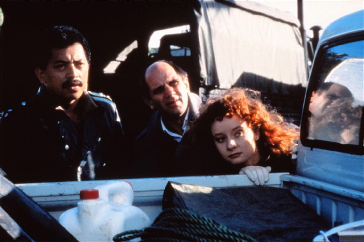 Tre persone si sporgono dal retro di un camion. Un uomo in uniforme a sinistra.