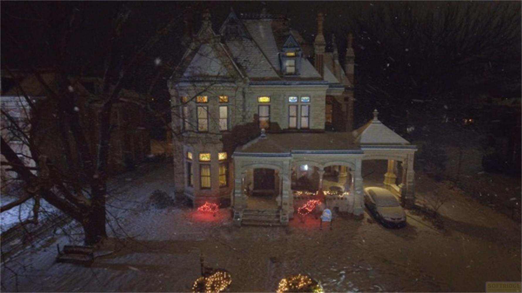 Una casa vittoriana innevata di notte, decorata con lucine.
