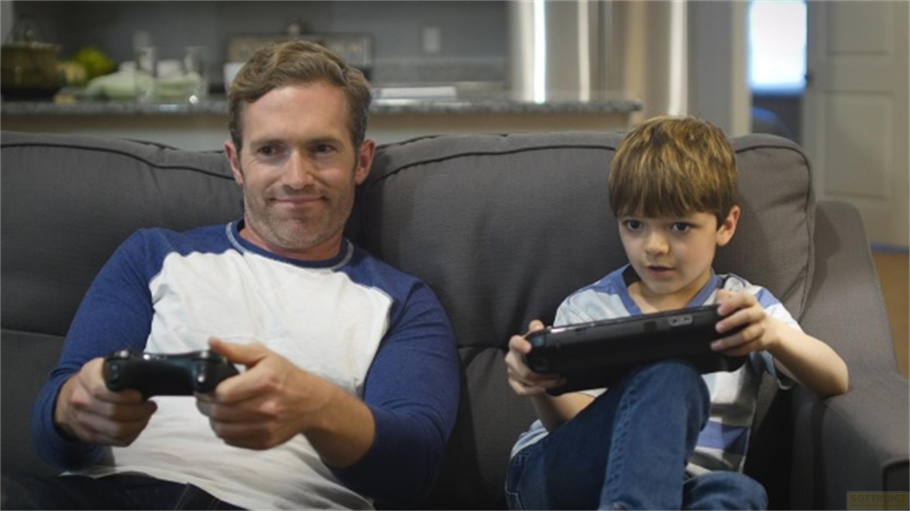Padre e figlio giocano ai videogiochi sul divano.