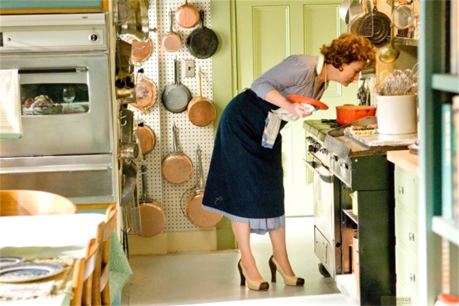 Una donna dai capelli rossi si china su un fornello a gas in una cucina.