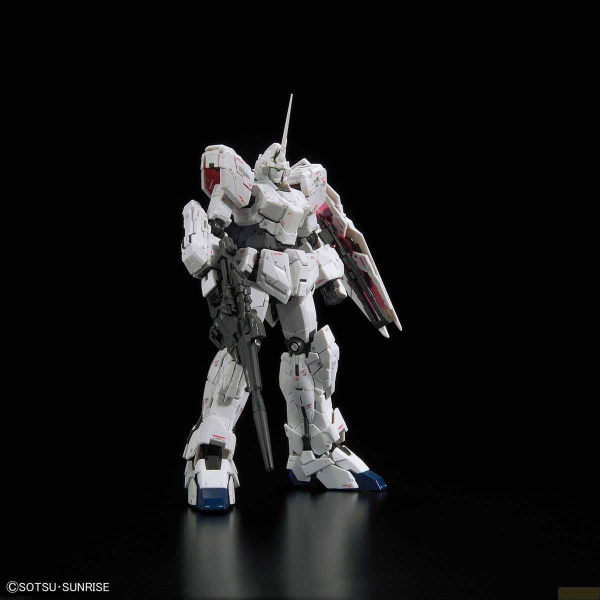 Ein weißer Gundam-Roboter mit Waffe steht vor schwarzem Hintergrund.